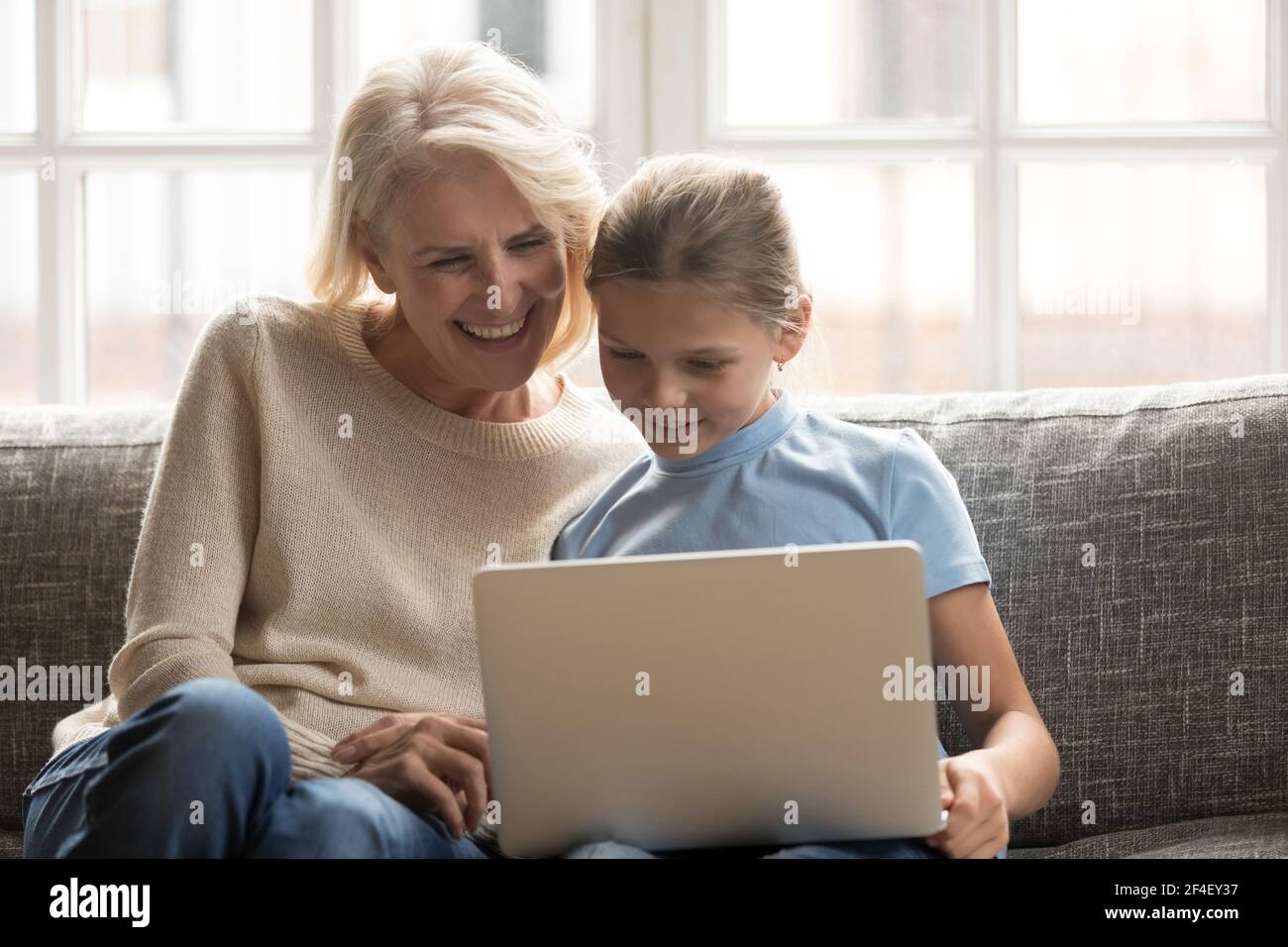Smiling grandmother and teen granddaughter use laptop Stock Photo