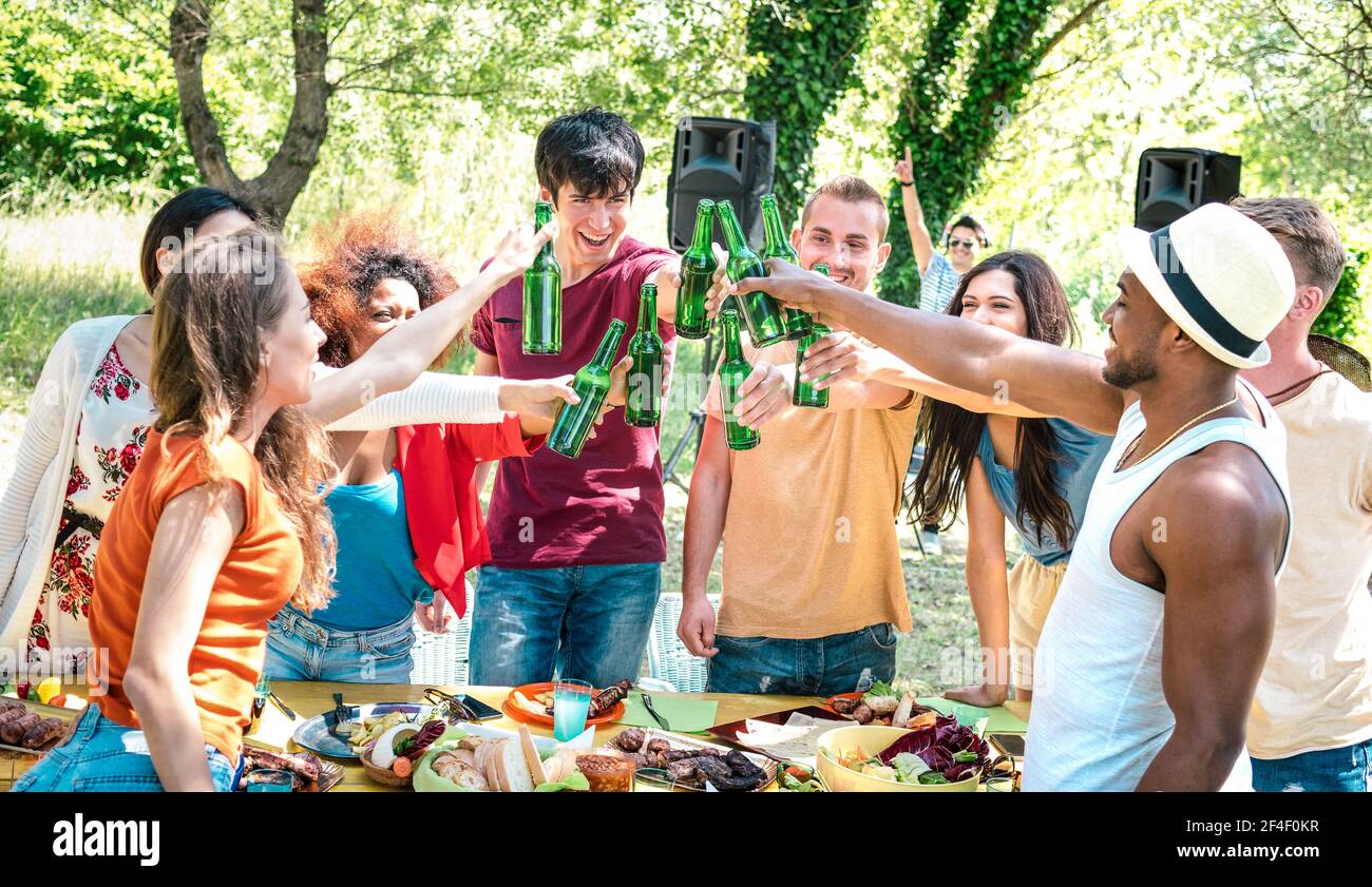 Happy multiracial friends toasting beer at barbecue garden party - Friendship concept with people having fun at backyard summer camp Stock Photo