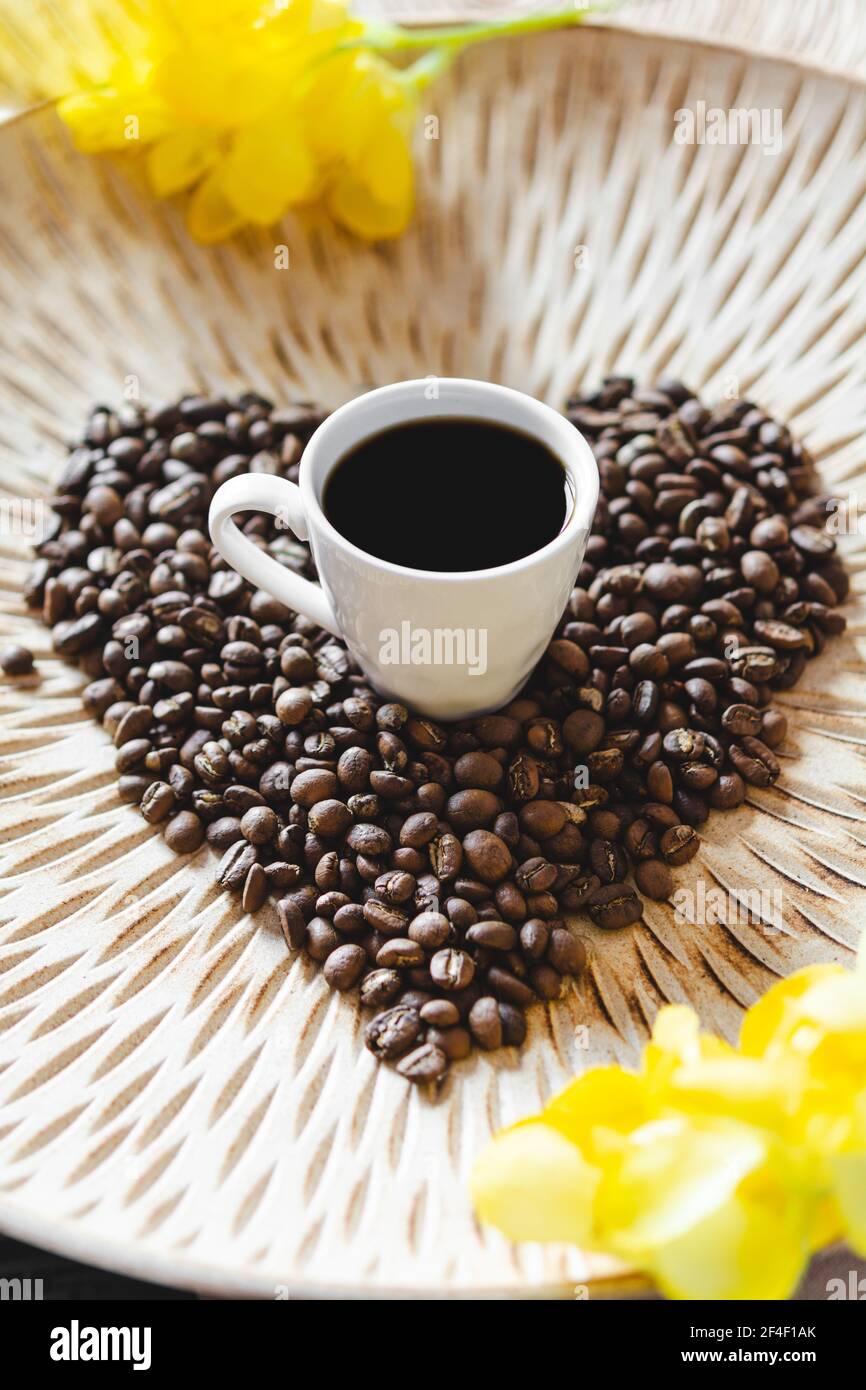 https://c8.alamy.com/comp/2F4F1AK/coffee-cup-beans-arabica-coffee-beans-in-the-form-of-a-heart-on-a-light-wooden-decorative-plate-with-a-pattern-a-cup-of-coffee-and-yellow-flowers-b-2F4F1AK.jpg