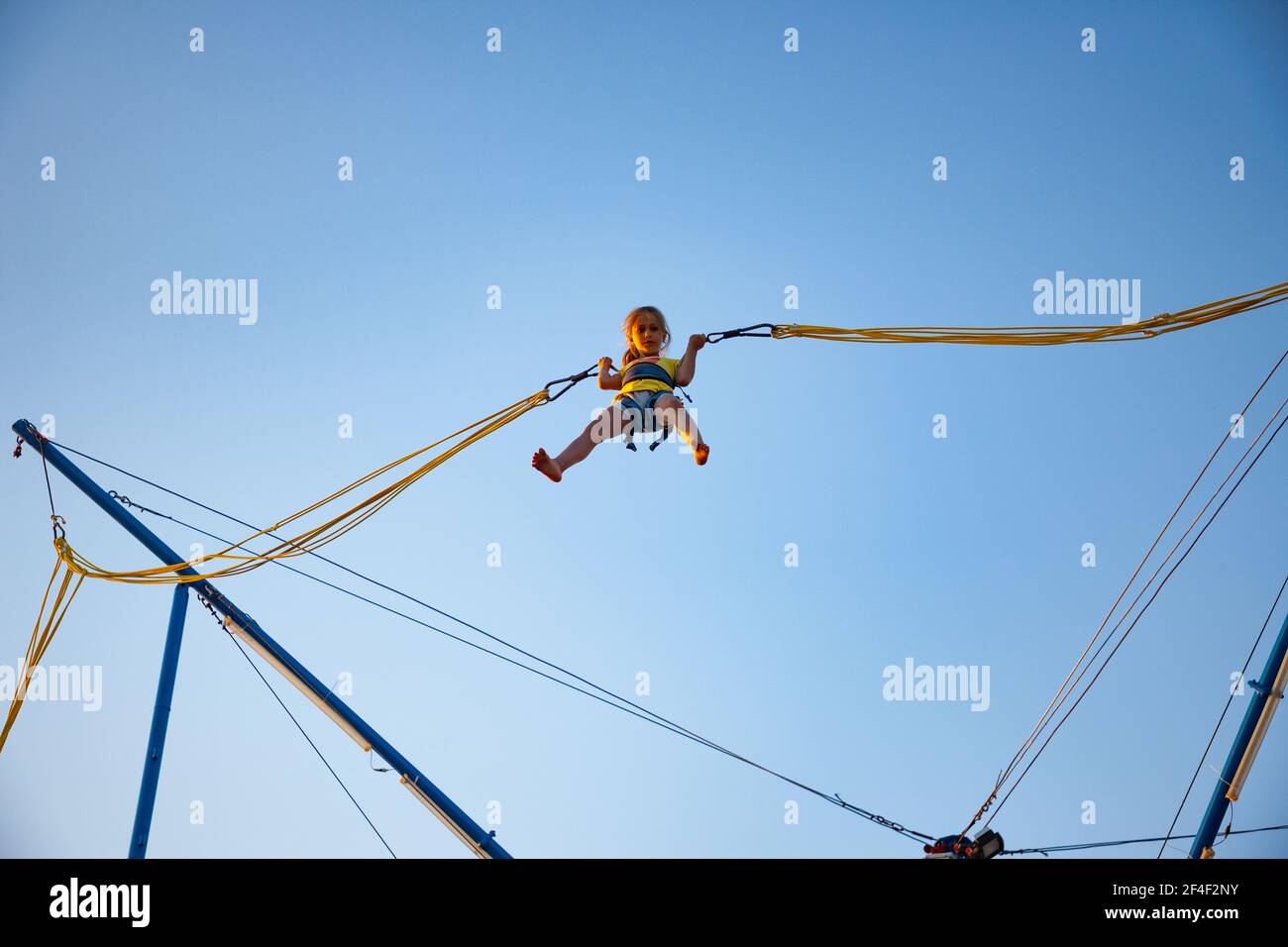 A little cheerful girl flies on springy bright elastic bands and jumps on a  trampoline enjoying the long-awaited vacation in the warm sun Stock Photo -  Alamy