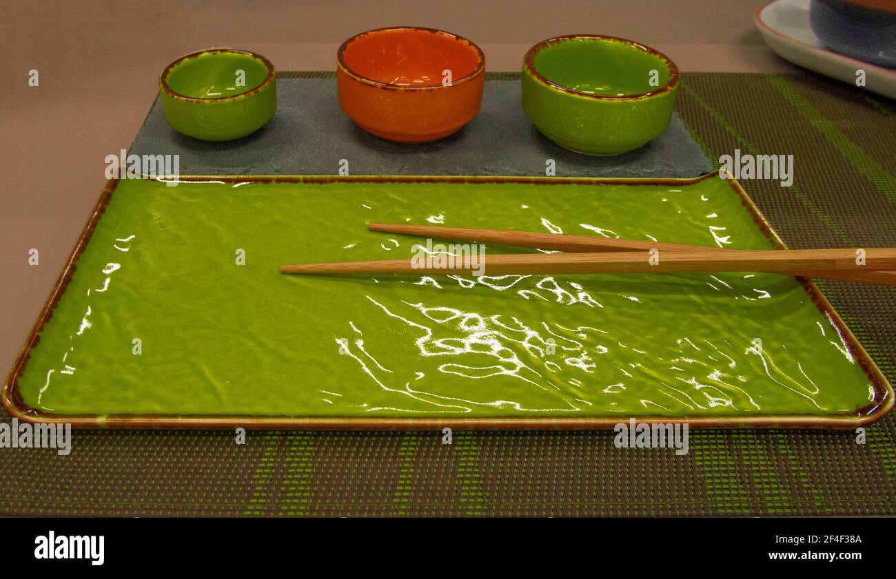 Kitchen accessories, lively green ceramic sushi set consisting of a  rectangular plate, bowls and wooden chopsticks Stock Photo - Alamy
