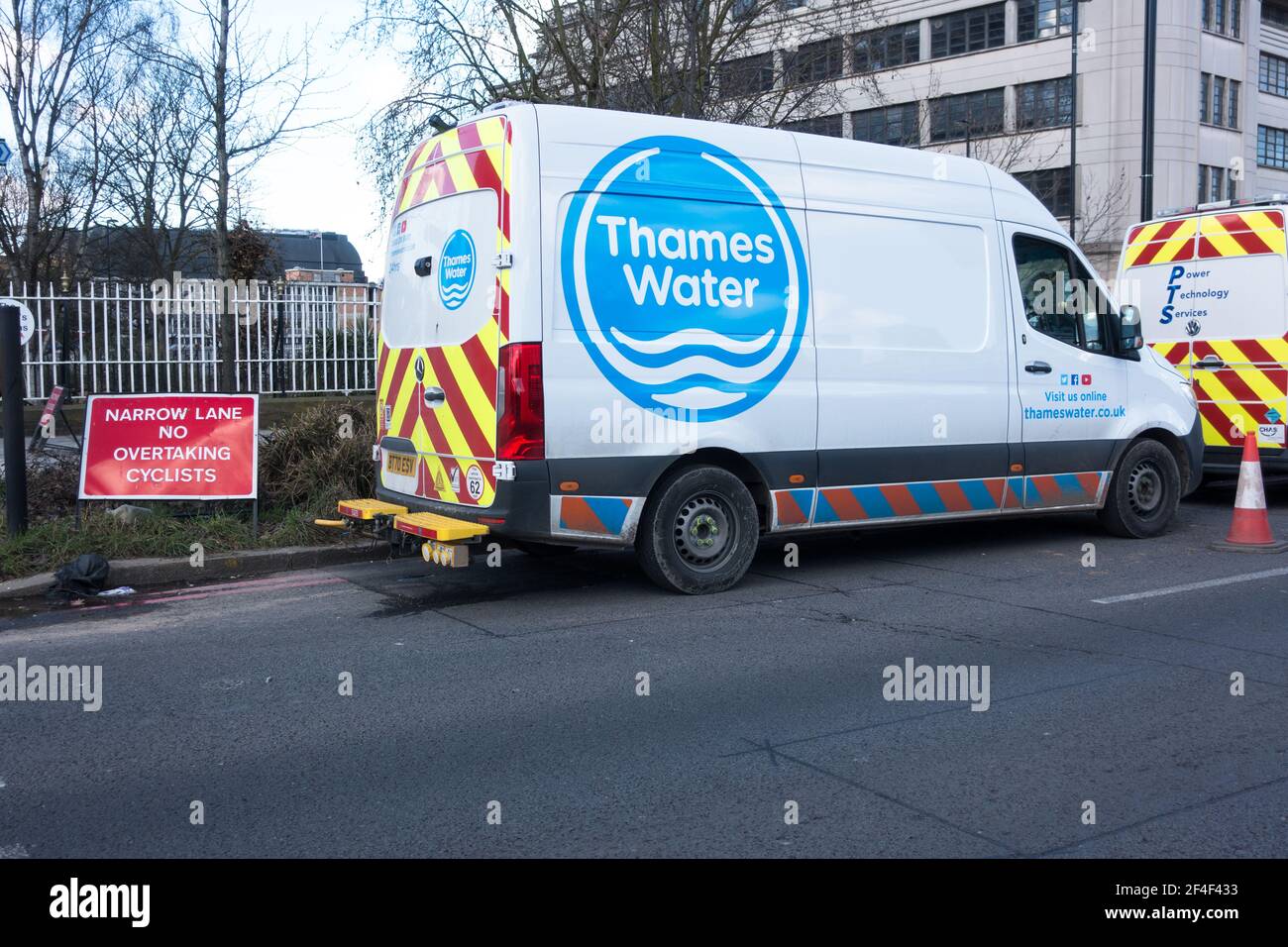 Thames Water van working on the street cutting down one lane on road with warning board not to overtake cyclist Stock Photo