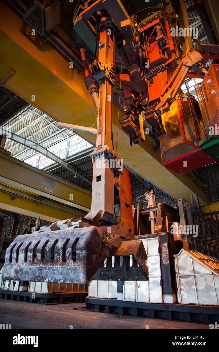 Pavlodar, Kazakhstan - May 05 2012:  Aluminum electrolysis plant. Slag handling crane with bucket and operator cabin. Electrolysis baths on background Stock Photo