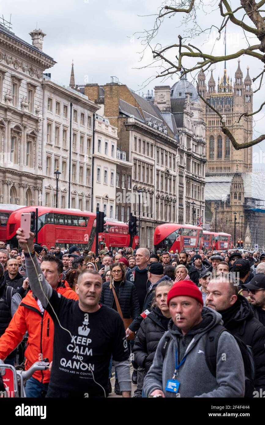 Crowds marching down Whitehall at a COVID 19 anti lockdown protest march in Westminster, London, UK. White Caucasian male with QAnon T shirt Stock Photo