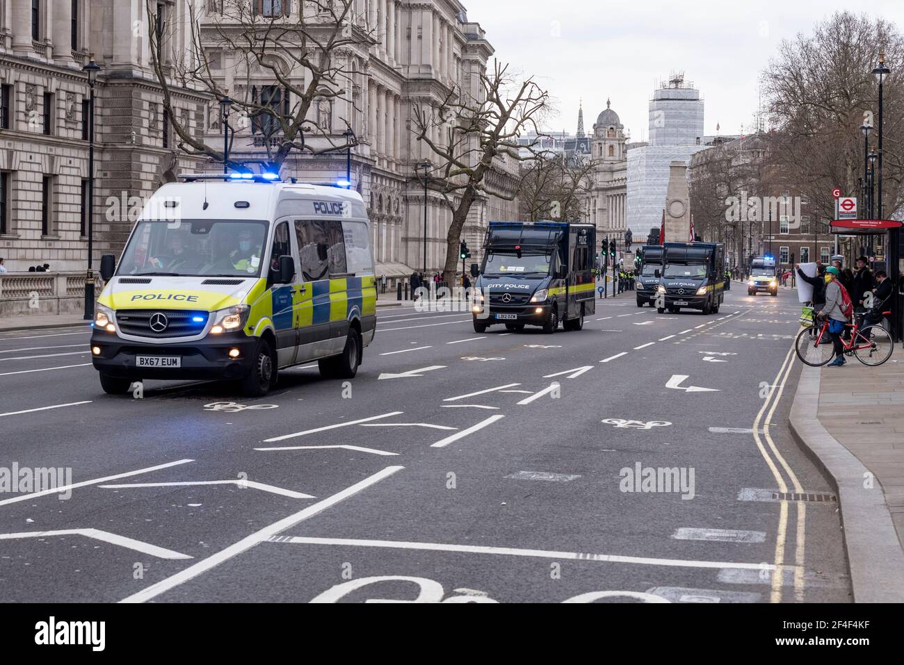 Fleet of police vans driving with blue lights to a call at a COVID 19 anti lockdown protest march in Westminster, London, UK. Whitehall Stock Photo