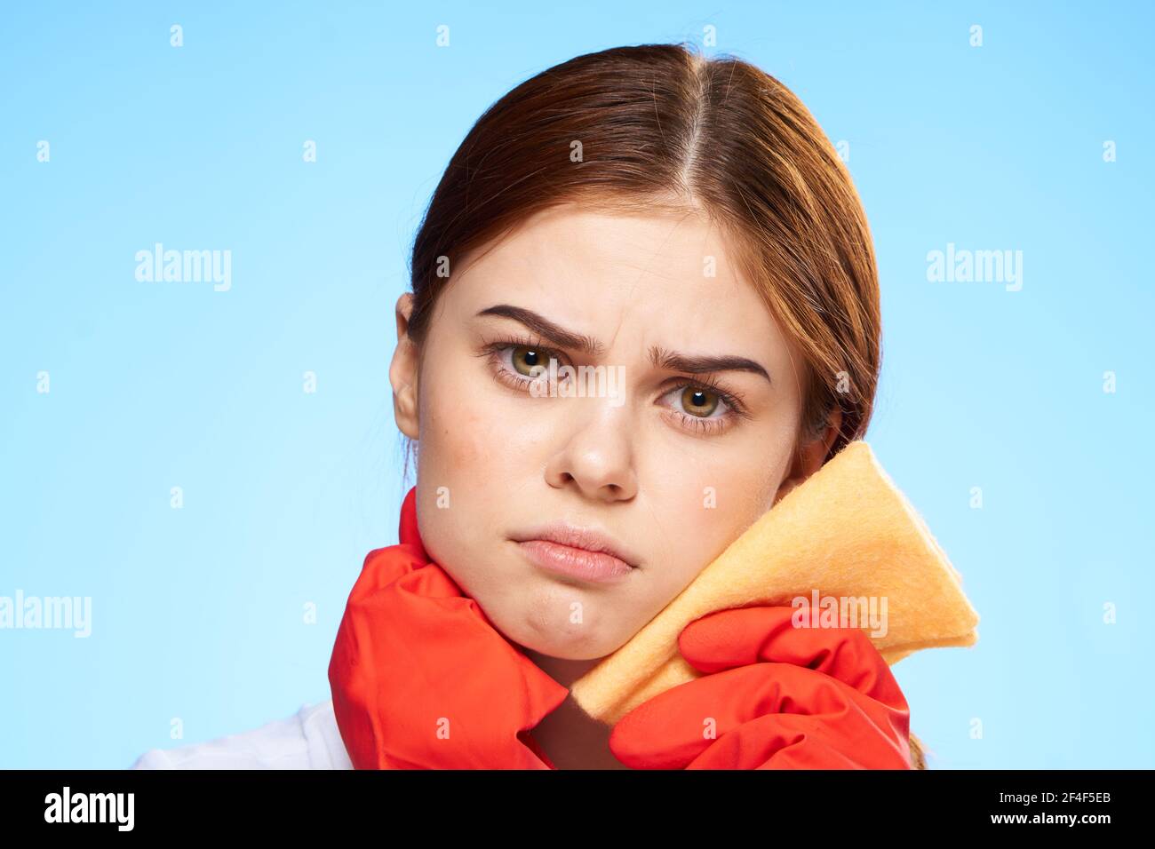 cleaning lady in rubber gloves holding a rag near face lifestyle blue ...