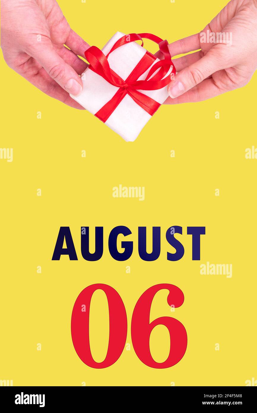 August 6th. Festive Vertical Calendar With Hands Holding White Gift Box With Red Ribbon And Calendar Date 6 August On Illuminating Yellow Background.S Stock Photo