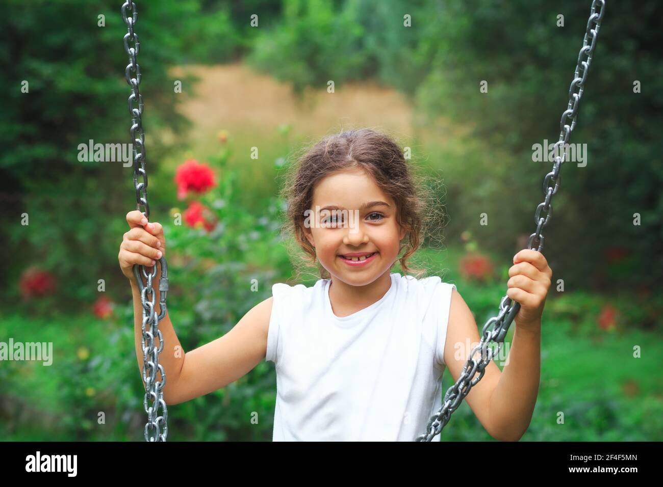 Child playing on outdoor playground. Kids play on school or kindergarten yard. Active kid on colorful swing. Healthy summer activity for children in s Stock Photo