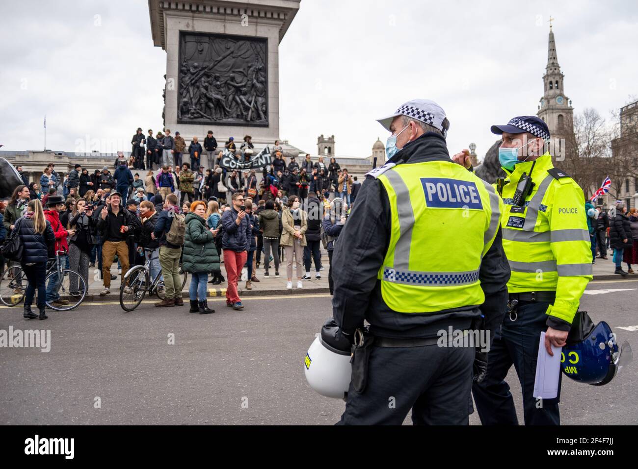 Police officers watching on as protesters gather in Trafalgar Square at a COVID 19 anti lockdown protest march in Westminster, London, UK. Face masks Stock Photo