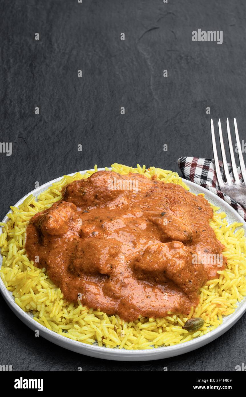 Chicken Tikka Masala with pilau rice on black stone background Stock