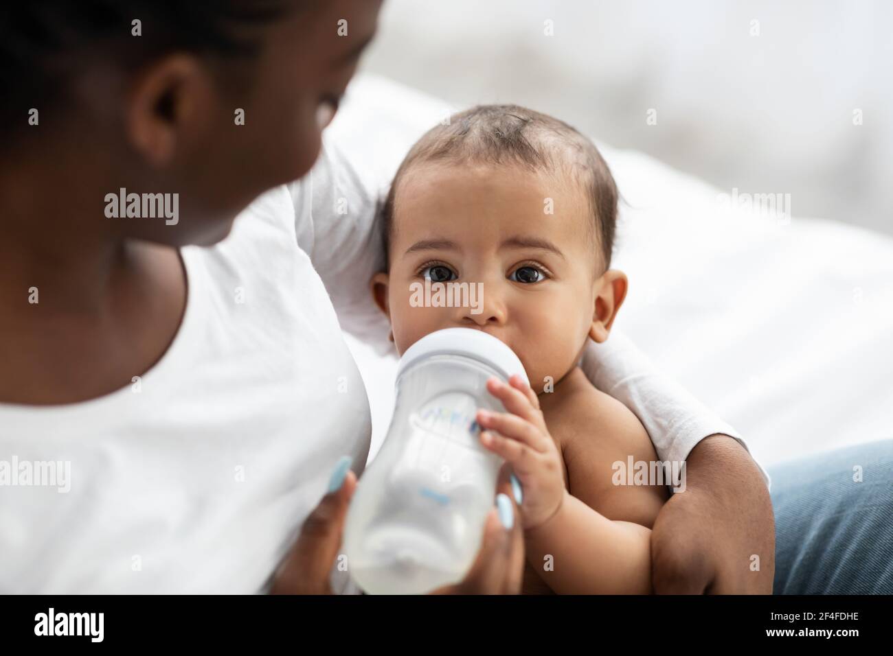 Cute little African American baby drinking from baby bottle Stock Photo