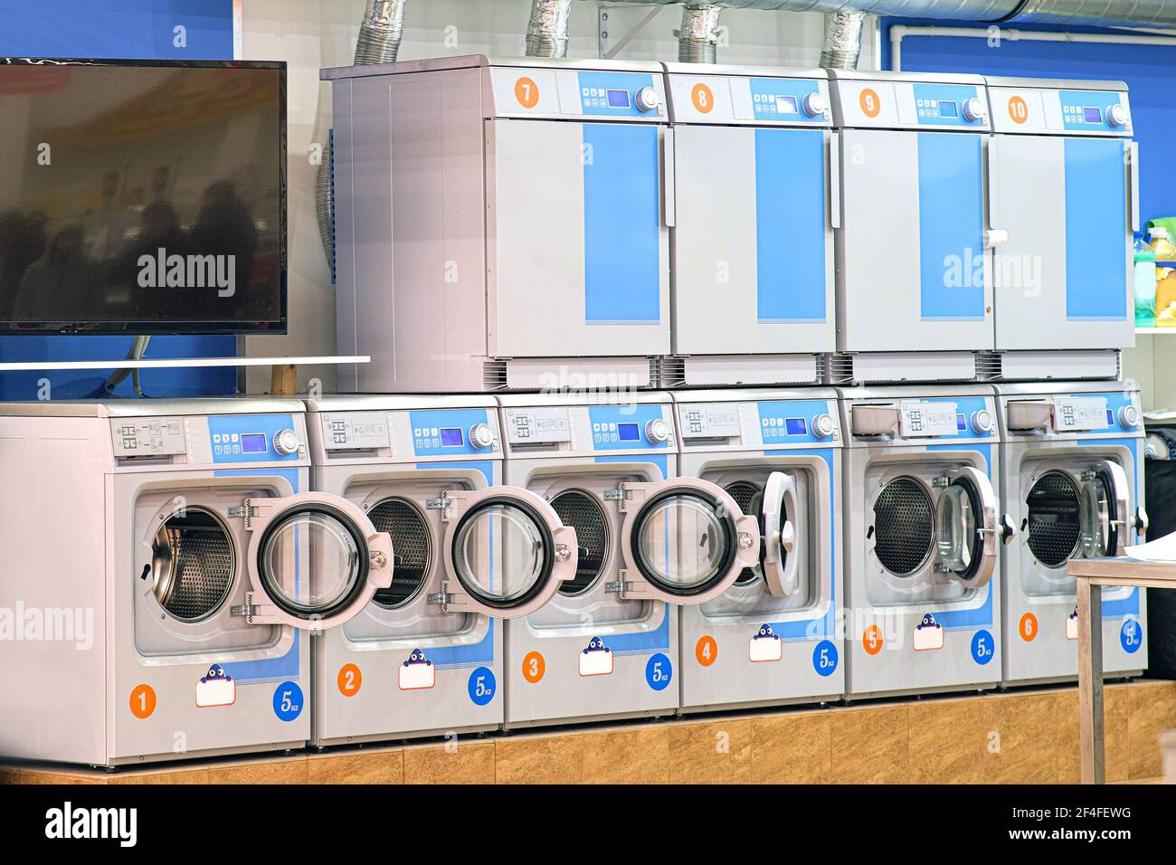 A number of industrial washing machines in the laundry room. The concept of self-service dry cleaning of fast laundry in the laundry plant Stock Photo