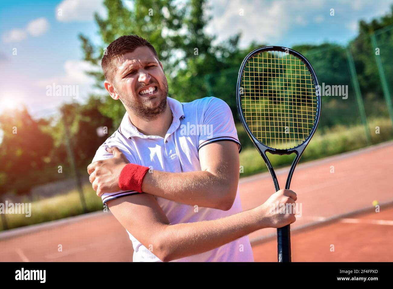 Shot of a tennis player with a shoulder injury on a clay court Stock