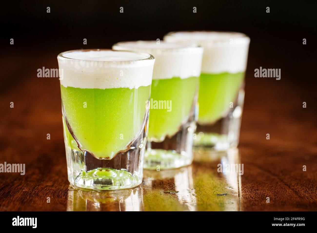 Three shot glasses of green alcoholic cocktails Stock Photo