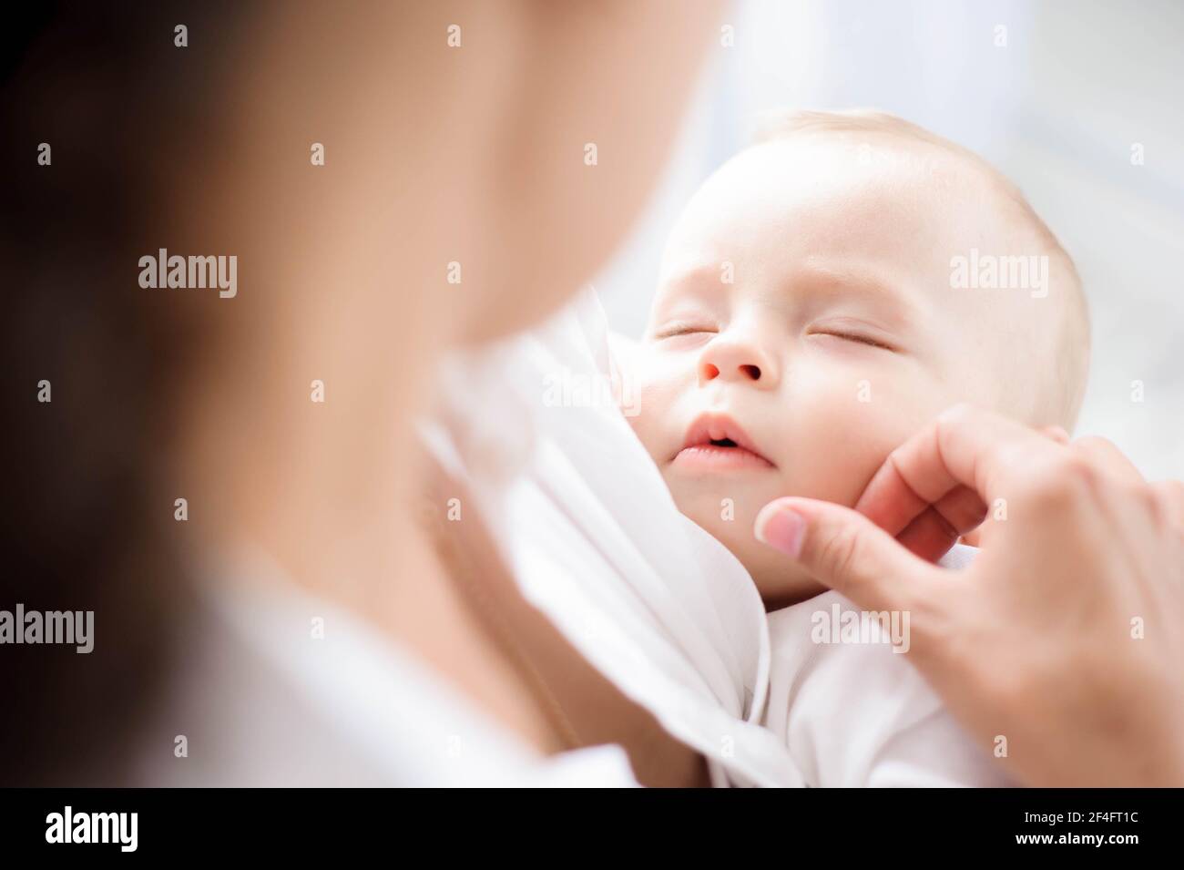 Baby sleeping on the mother's chest. Young mother cuddling baby Stock