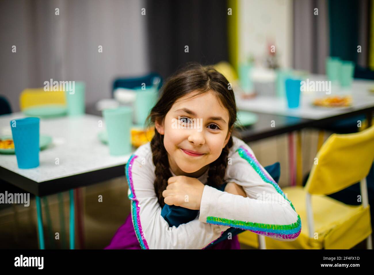 The cheerful little girl is sitting on a chair in a cafe Stock Photo ...