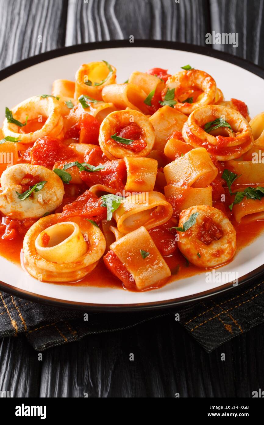 Calamarata pasta with squid sauce a traditional neapolitan recipe close-up in a plate on the table. vertical Stock Photo