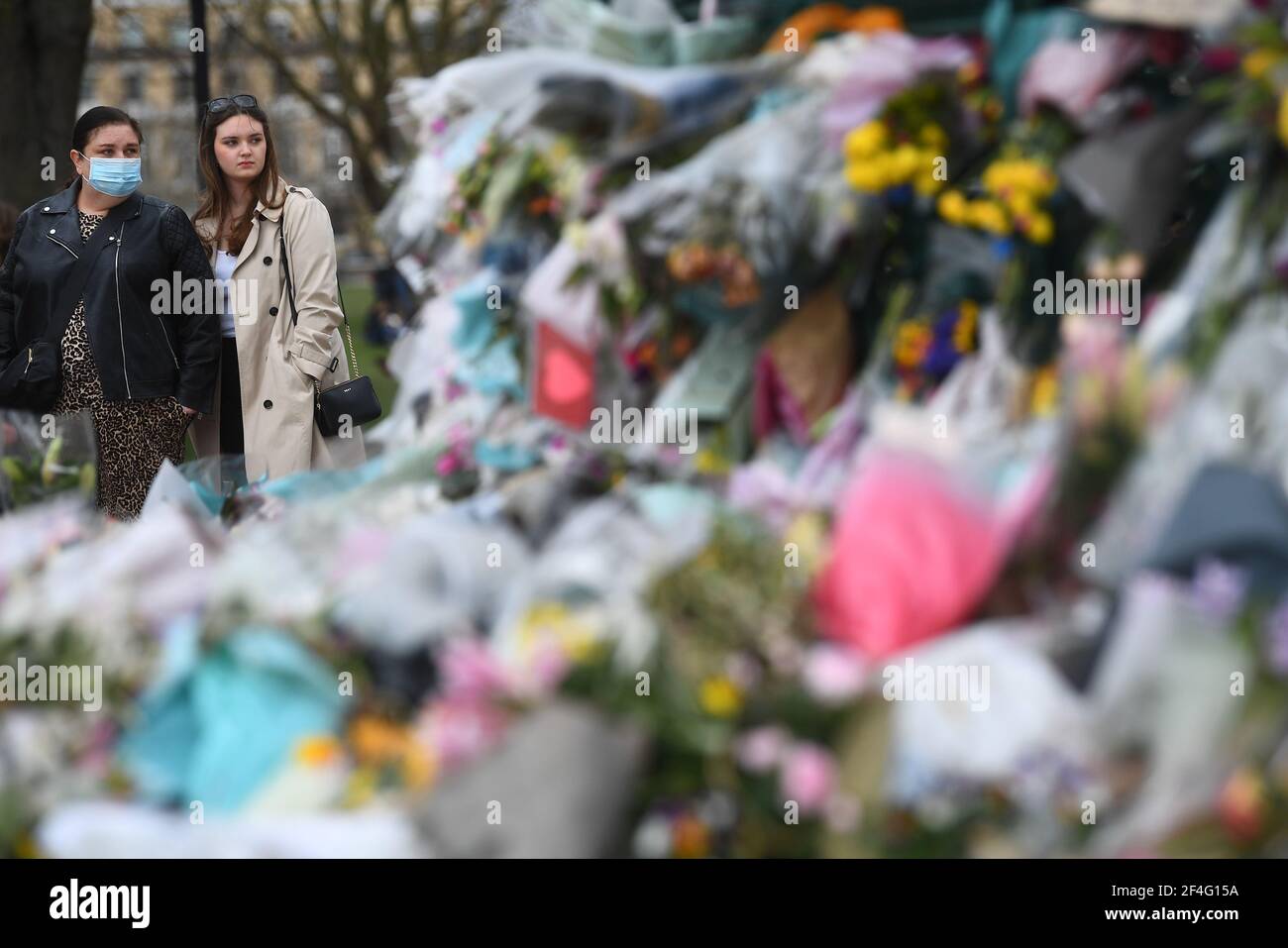 People viewing floral tributes left at the bandstand in Clapham Common, London, for Sarah Everard. Pc Wayne Couzens, 48, appeared at the Old Bailey in London charged with the kidnap and murder of the 33-year-old. Picture date: Sunday March 21, 2021. Stock Photo