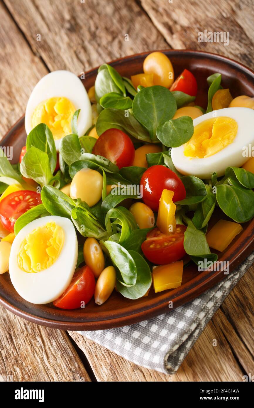 Fresh salad of lupine beans, eggs, tomatoes and Valerianella locusta close-up in a plate on the table. vertical Stock Photo