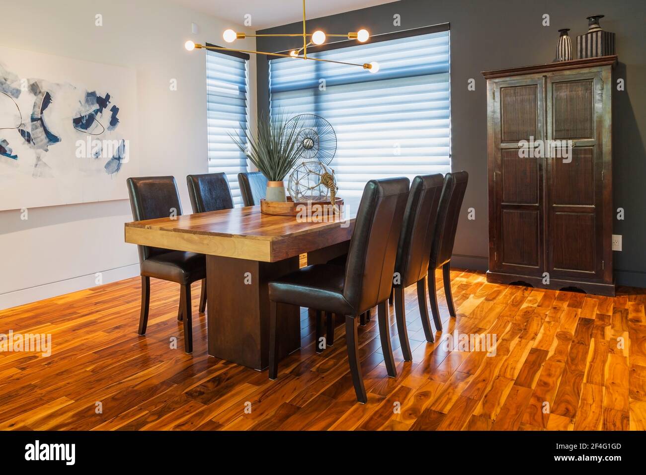 Rosewood dining table with dark brown leather high back chairs and antique  wooden armoire in dining room with acacia wood floorboards Stock Photo -  Alamy