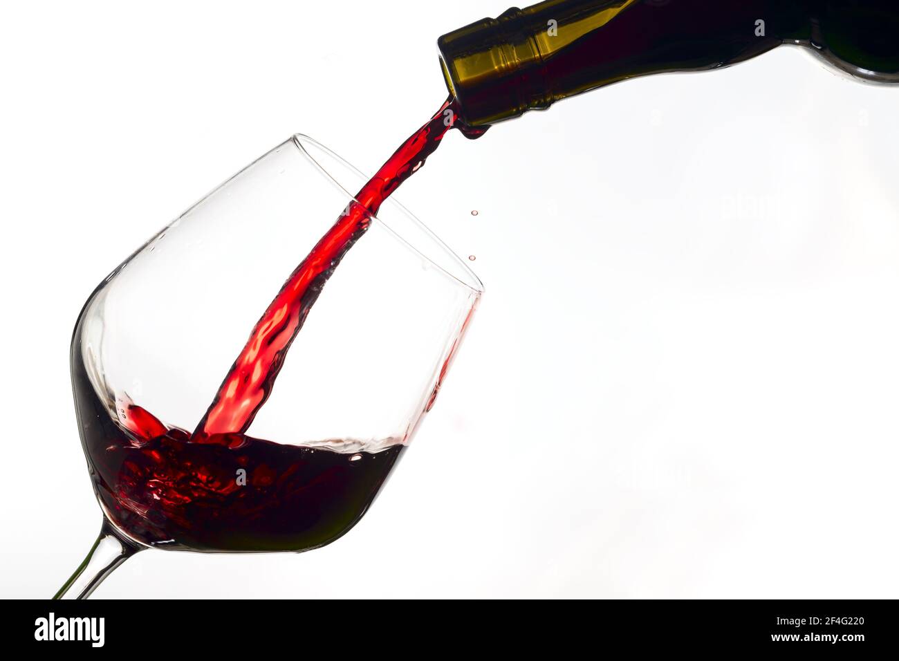 red wine poured from a bottle into wine glass on white background