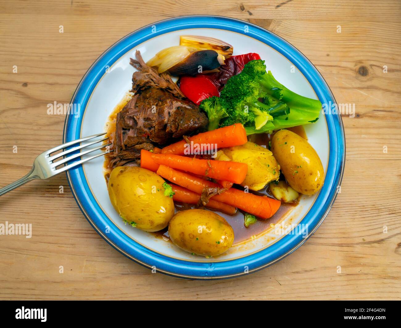 Sunday Lunch main course tender peppery British Beef new potatoes grilled peppers shallots  carrots and broccoli  with red wine gravy Stock Photo