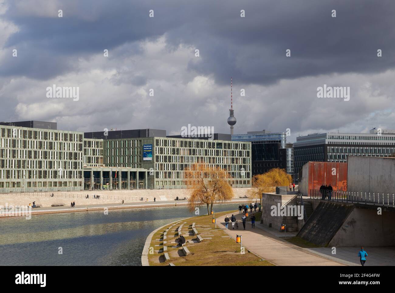 Berlin, Germany. 21st Mar, 2021. People walk under thick dark clouds on the banks of the Spree between the central station and the government district. After a gloomy start to the week, a new high brings spring to many places in Germany. Credit: Annette Riedl/dpa/Alamy Live News Stock Photo