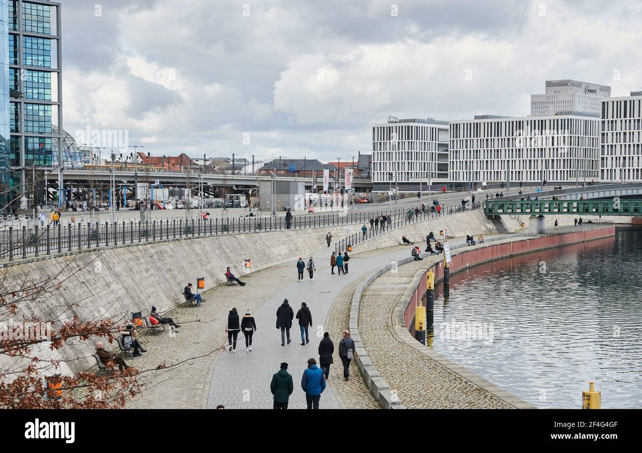 Berlin, Germany. 21st Mar, 2021. People walk along the banks of the Spree between the central station and the government district. After a gloomy start to the week, a new high brings spring to many places in Germany. Credit: Annette Riedl/dpa/Alamy Live News Stock Photo