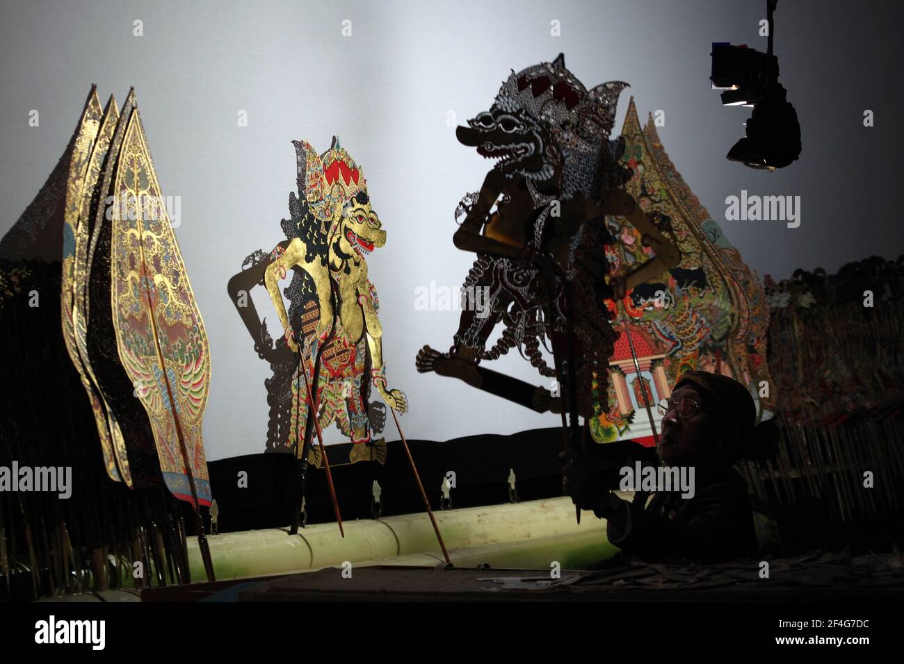 Puppet master (dalang) Manteb Sudharsono performs the wayang kulit performance 'Sudamala' in the Sasono Hinggil Theatre in Yogyakarta, Central Java, Indonesia. Traditional puppet shadow theatre known as wayang kulit is widespread on the islands of Java and Bali in Indonesia. Each wayang kulit performance continues about eight hours through the night without intermissions and only one puppet master (dalang) conducts all puppets projected on a linen screen and vocalizes them with different voices. Although Indonesia is the most populated Muslim country in the world, stories and characters of way Stock Photo