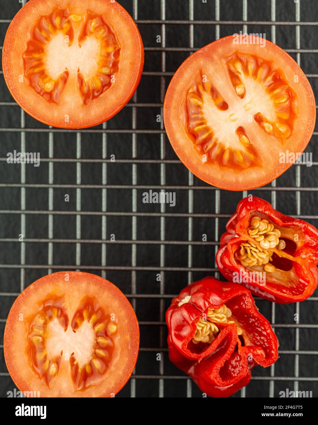 Sliced tomatoes and chilli peppers on a wire rack Stock Photo