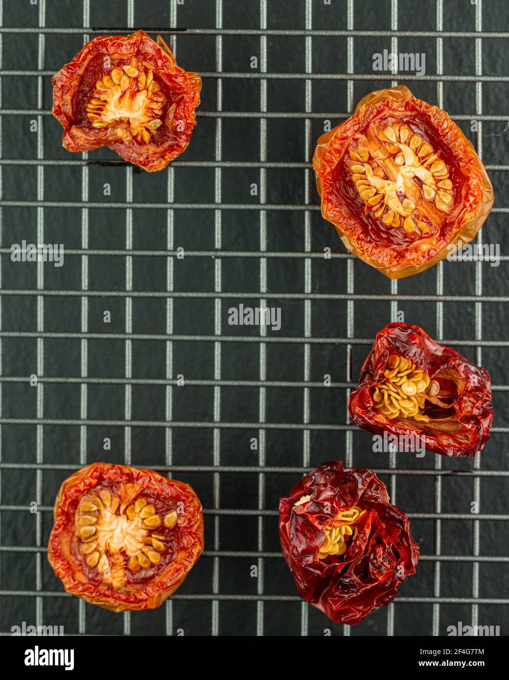 Sliced and dried tomatoes and chilli peppers on a wire rack Stock Photo