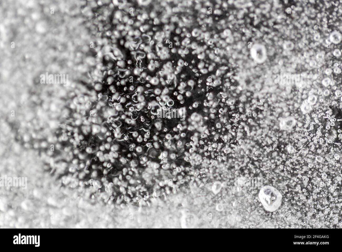 Macro shot of tiny air bubbles trapped in a sheet of ice in the garden, shot with a flash strobe light to illuminate the ice Stock Photo