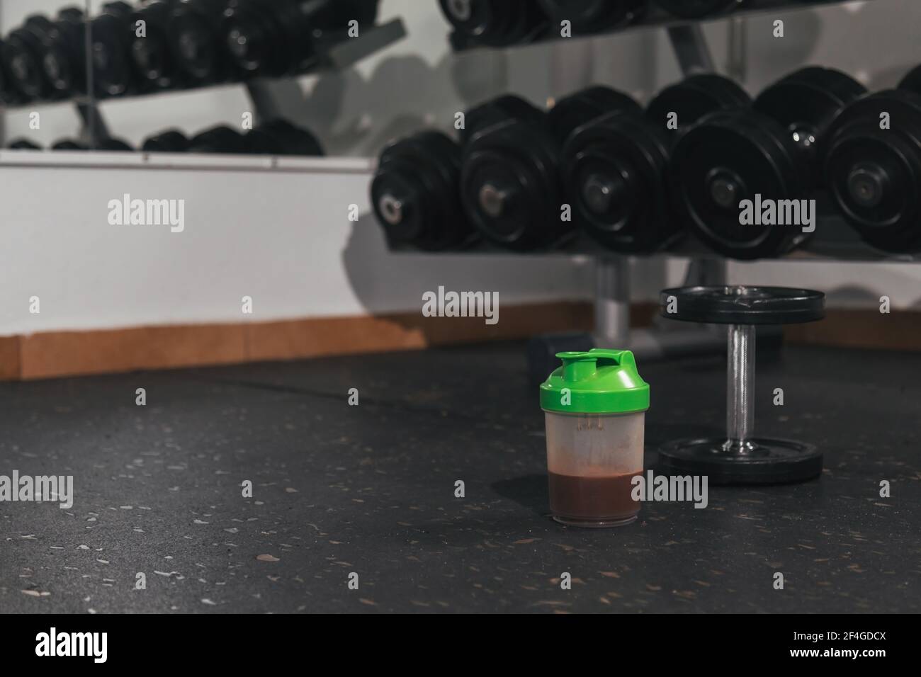 Protein shake and dumbbells at the gym. Fitness nutrition drink and heavy weights.P Stock Photo