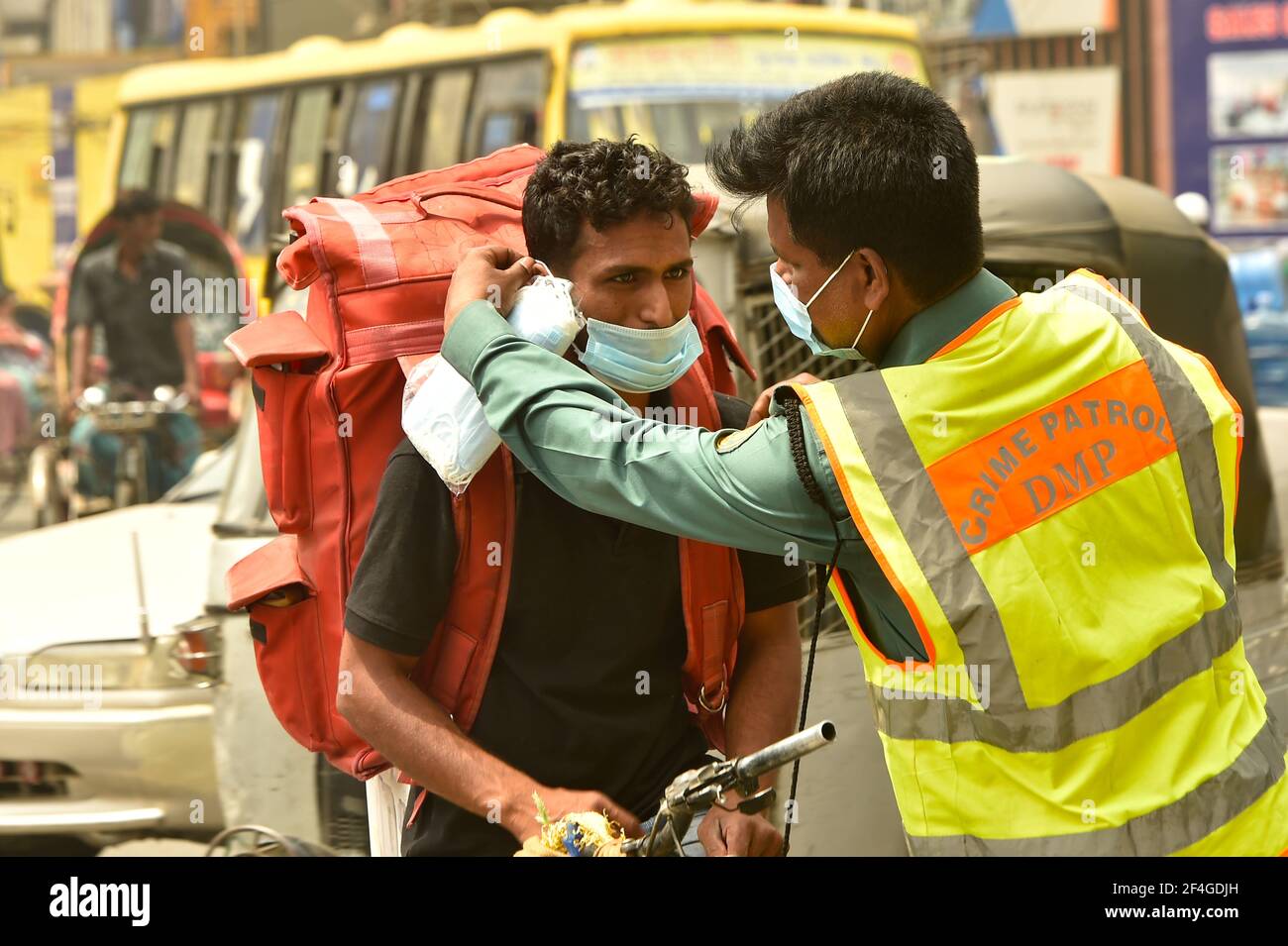 Dhaka. 21st Mar, 2021. A policeman gives a mask to a rickshaw puller on a street in Dhaka, Bangladesh, March 21, 2021. Bangladesh government is emphasizing on the use of masks to contain the spread of the COVID-19 pandemic. Credit: Xinhua/Alamy Live News Stock Photo