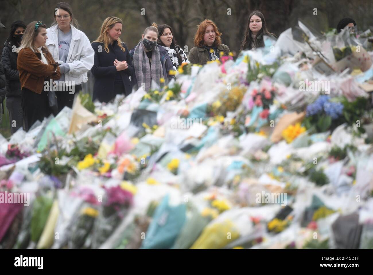 People viewing floral tributes left at the bandstand in Clapham Common, London, for Sarah Everard. Pc Wayne Couzens, 48, appeared at the Old Bailey in London charged with the kidnap and murder of the 33-year-old. Picture date: Sunday March 21, 2021. Stock Photo