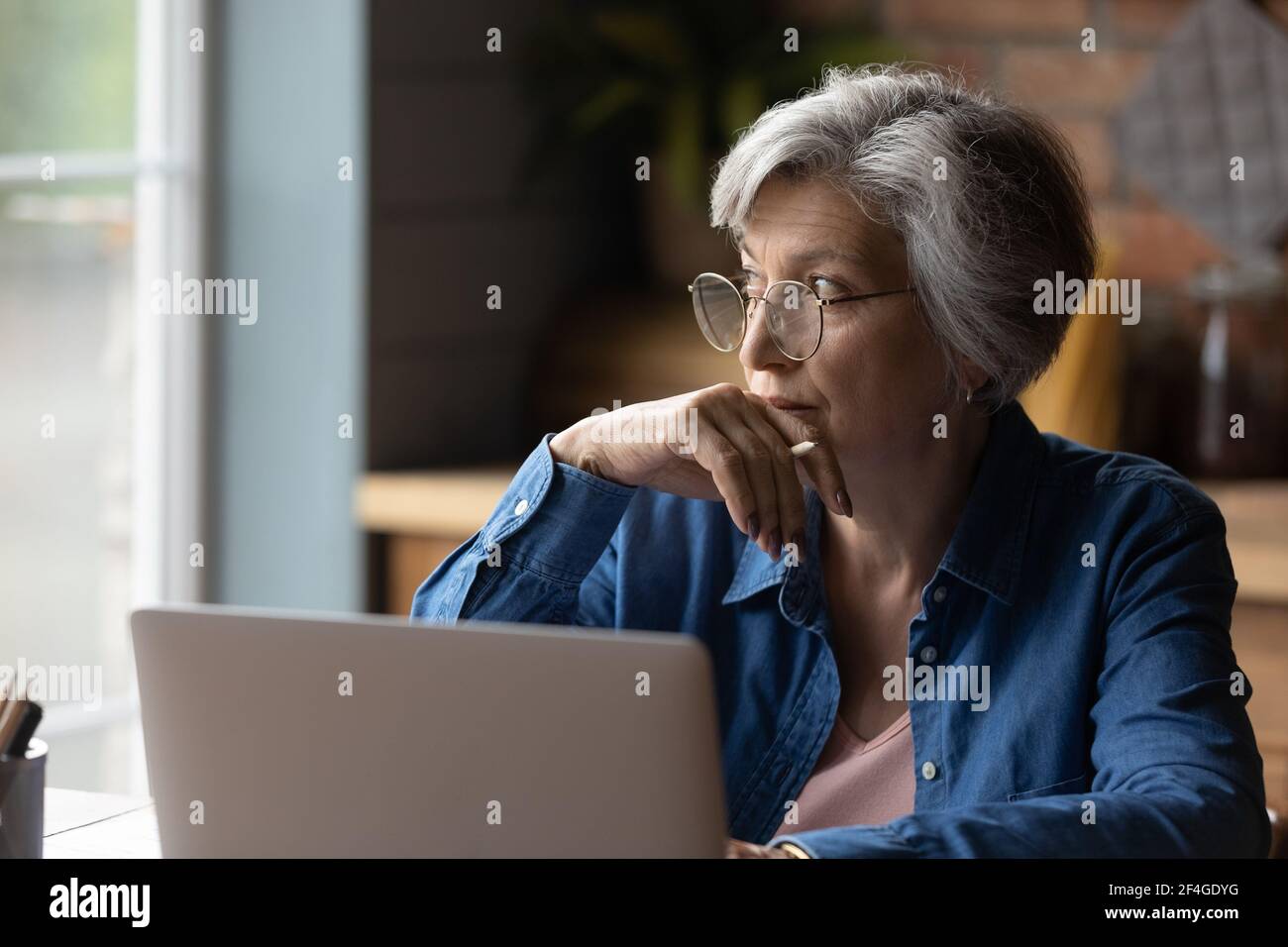 Pensive lady retiree study computer ponder on next step Stock Photo