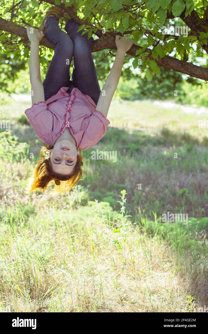 Cheerful girl hanging on a tree upside down Stock Photo