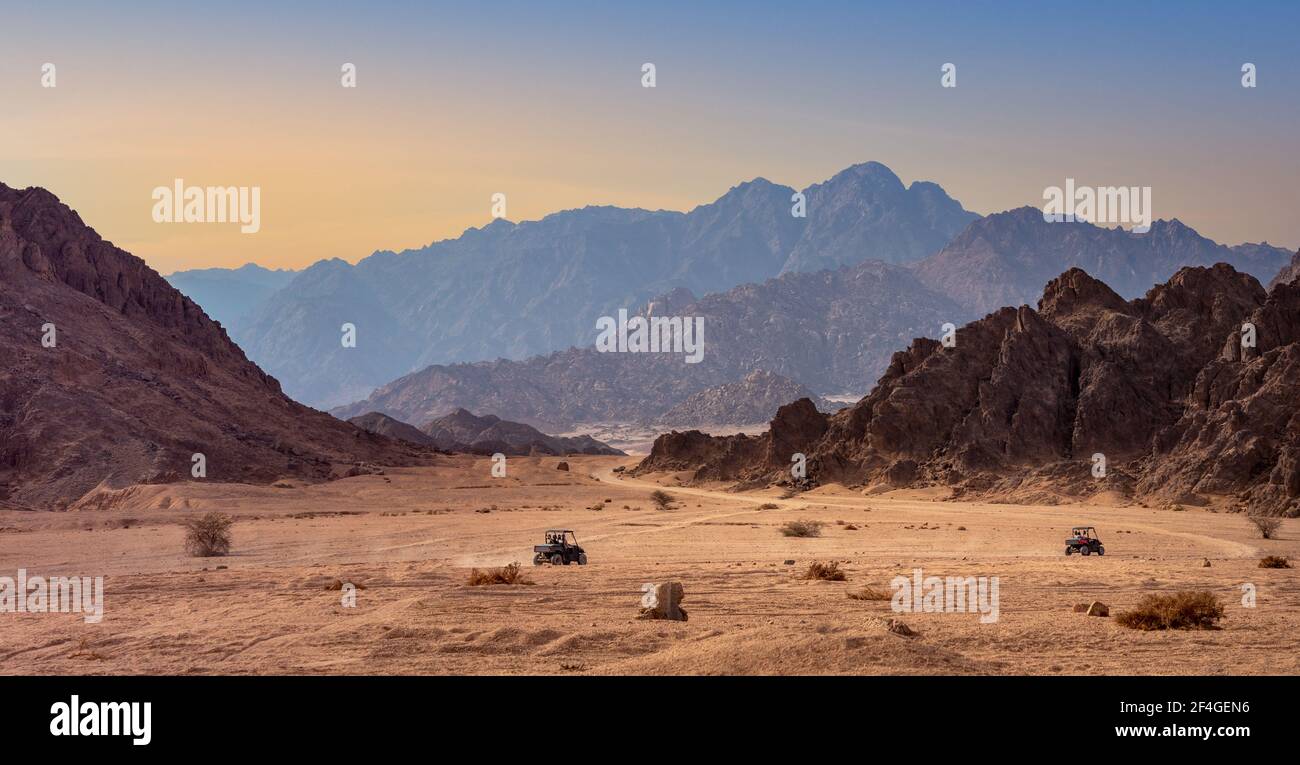 Buggy trip in a stone desert at sunset. Mountain landscape with off-road vehicles with tourists in Sharm el-Sheikh. Stock Photo