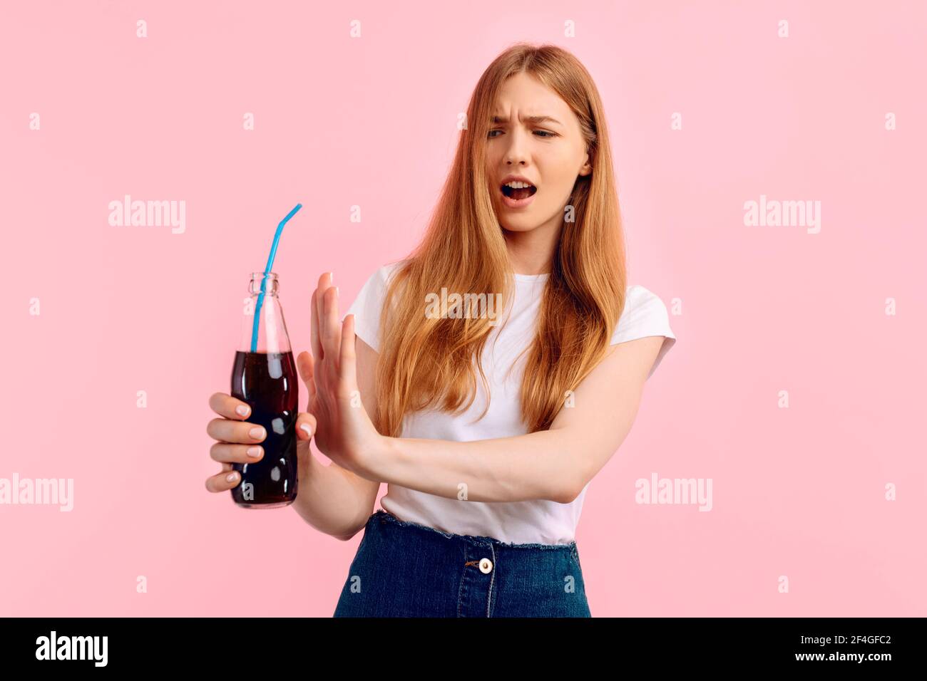 Young woman, against carbonated drinks, refuse carbonated soft drinks, on pink background Stock Photo