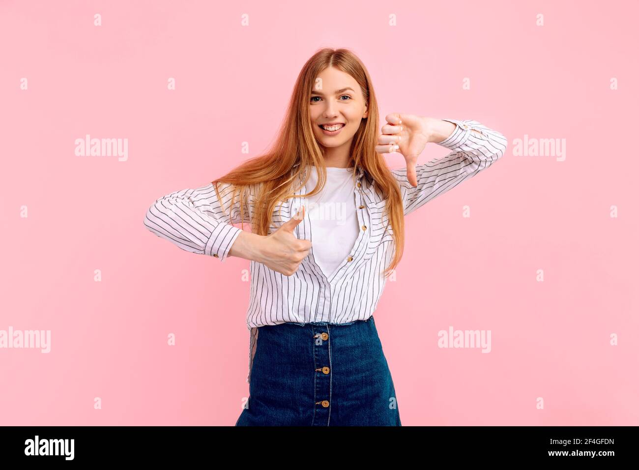 Young woman making good bad sign. Undecided yes or no on isolated pink ...