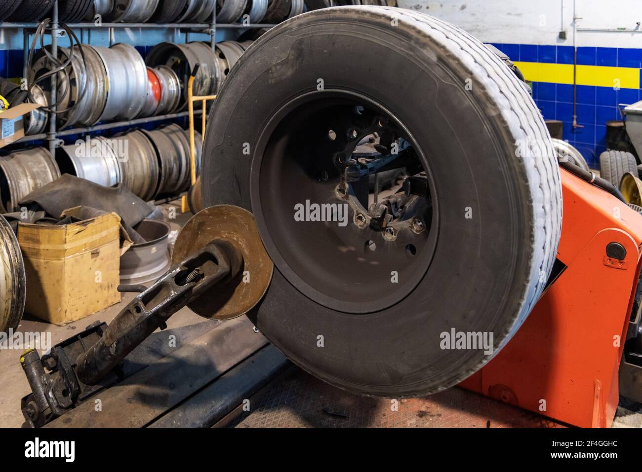 Tire workshop operator who uses a machine to mount or remove a truck wheel. Stock Photo