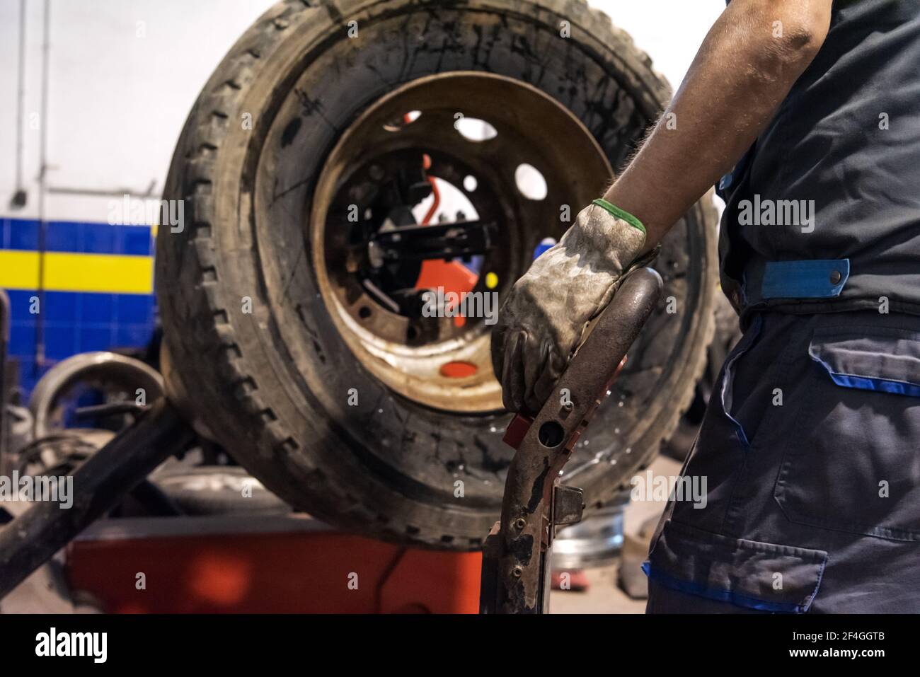 Tire workshop operator who uses a machine to mount or remove a truck wheel. Stock Photo