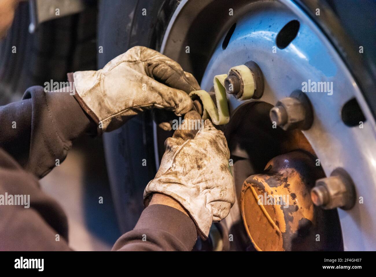 Tire workshop operator who uses a machine to mount or remove a truck wheel. Stock Photo