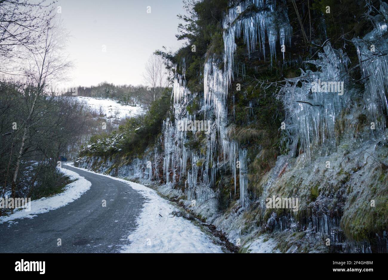 Dangerous winter conditions on a road after a freezing night leave the slopes covered in icicles in the Courel mountain range Stock Photo