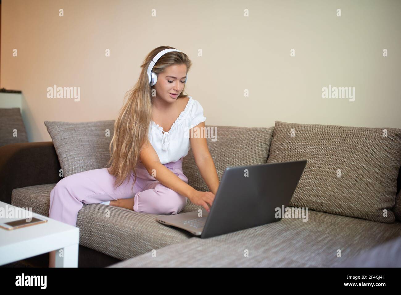 Young woman using a laptop while relaxing on the couch Stock Photo - Alamy