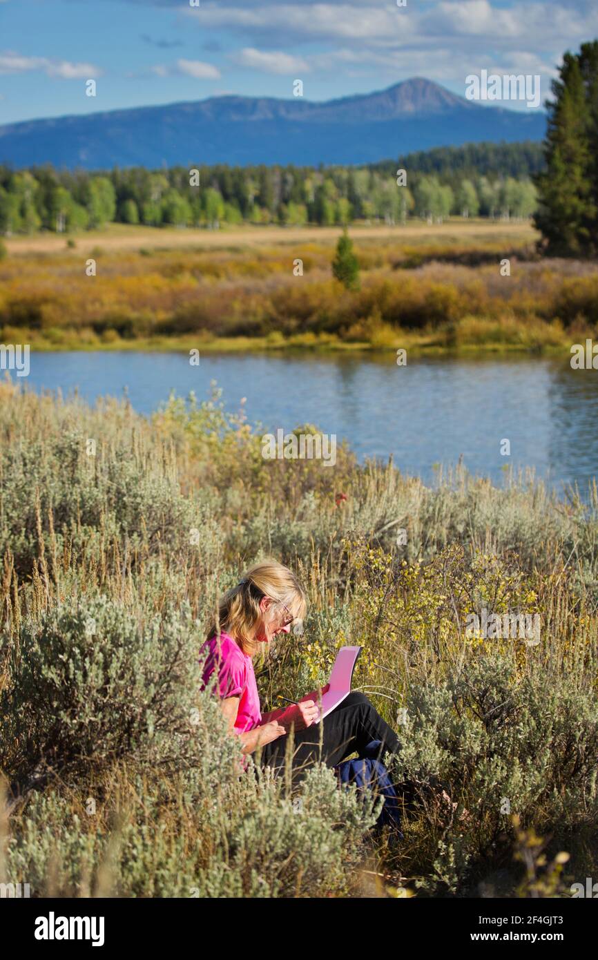 A woman sketching outdoors in summer Stock Photo