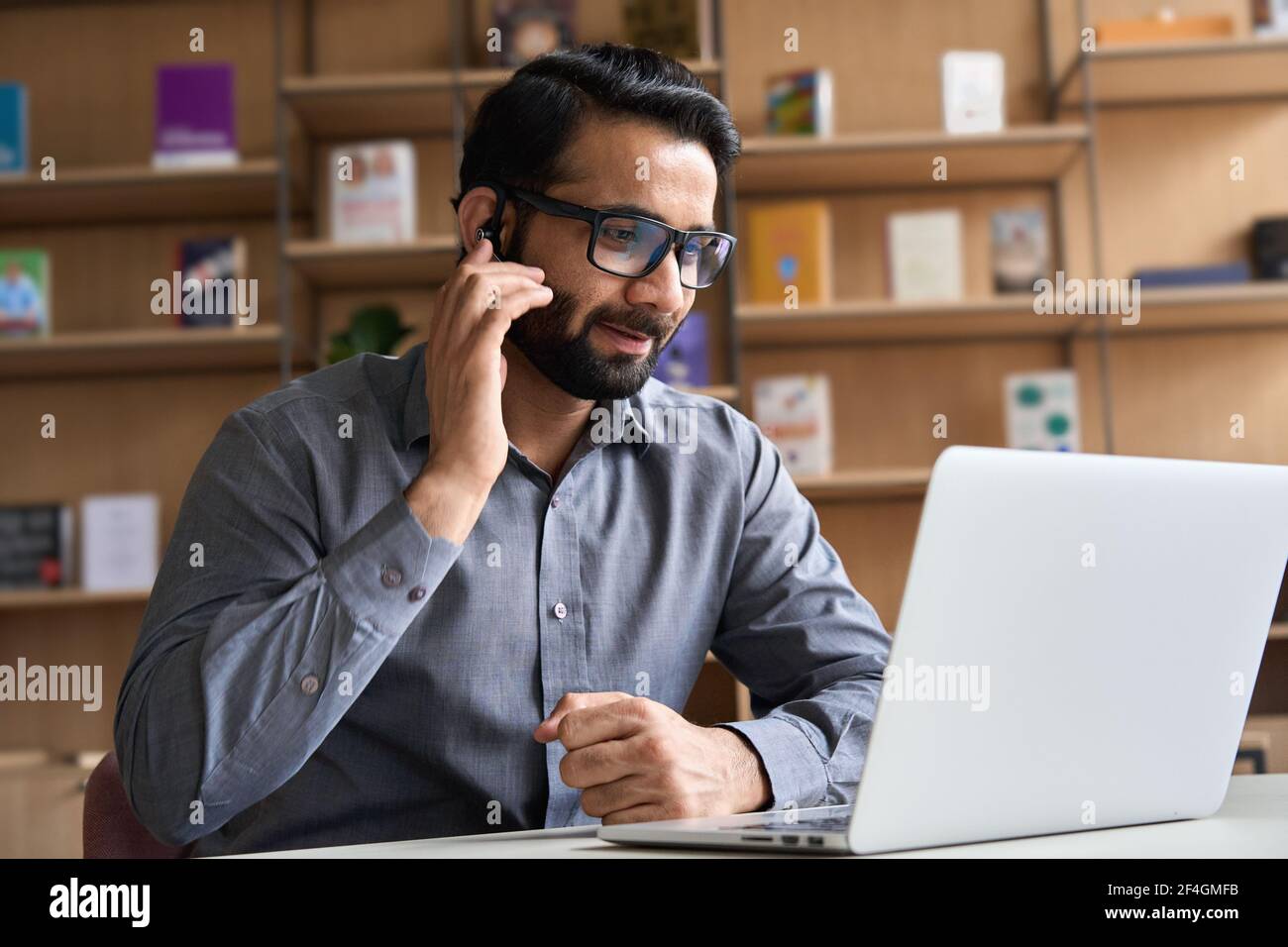 Indian customer support manager wearing headset consulting client on video call. Stock Photo