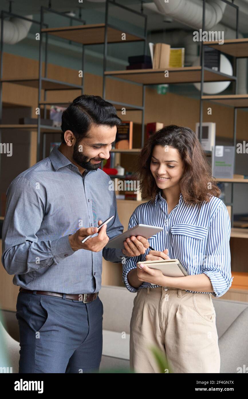 Diverse friendly coworkers talking using digital tablet in office. Stock Photo