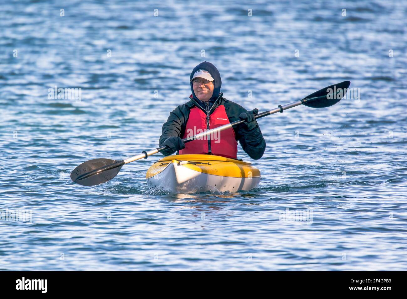 A middle aged man enjoying a late winter kayak adventure in the shipping canal connecting the bay of Green Bay with Lake Michigan near Sturgeon Bay Wi Stock Photo