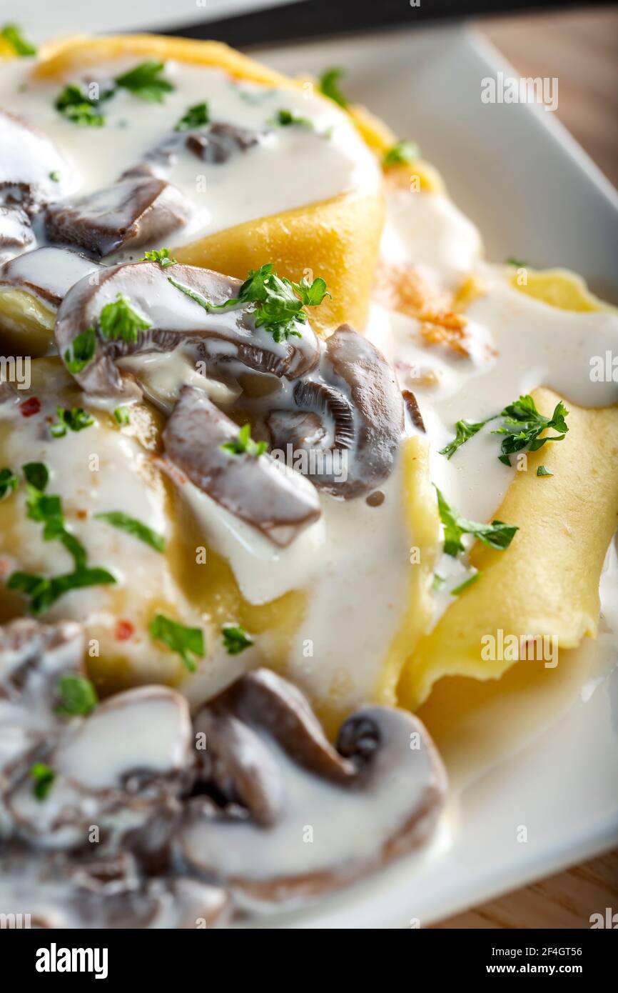 Ravioli filled with mozzarella cheese and red pepper with cream and mushrooms sauce on plate Stock Photo